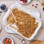 White enamel oven tray with baked granola and serving spoon